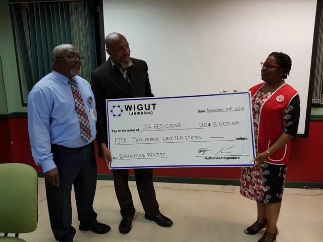Caption: WIGUT (Jamaica) President Prof. Paul Brown, and Treasurer Dr. Noel Morgan, handing over a donation cheque to President of the Jamaica Red Cross Society Ms. Hope Monroe.